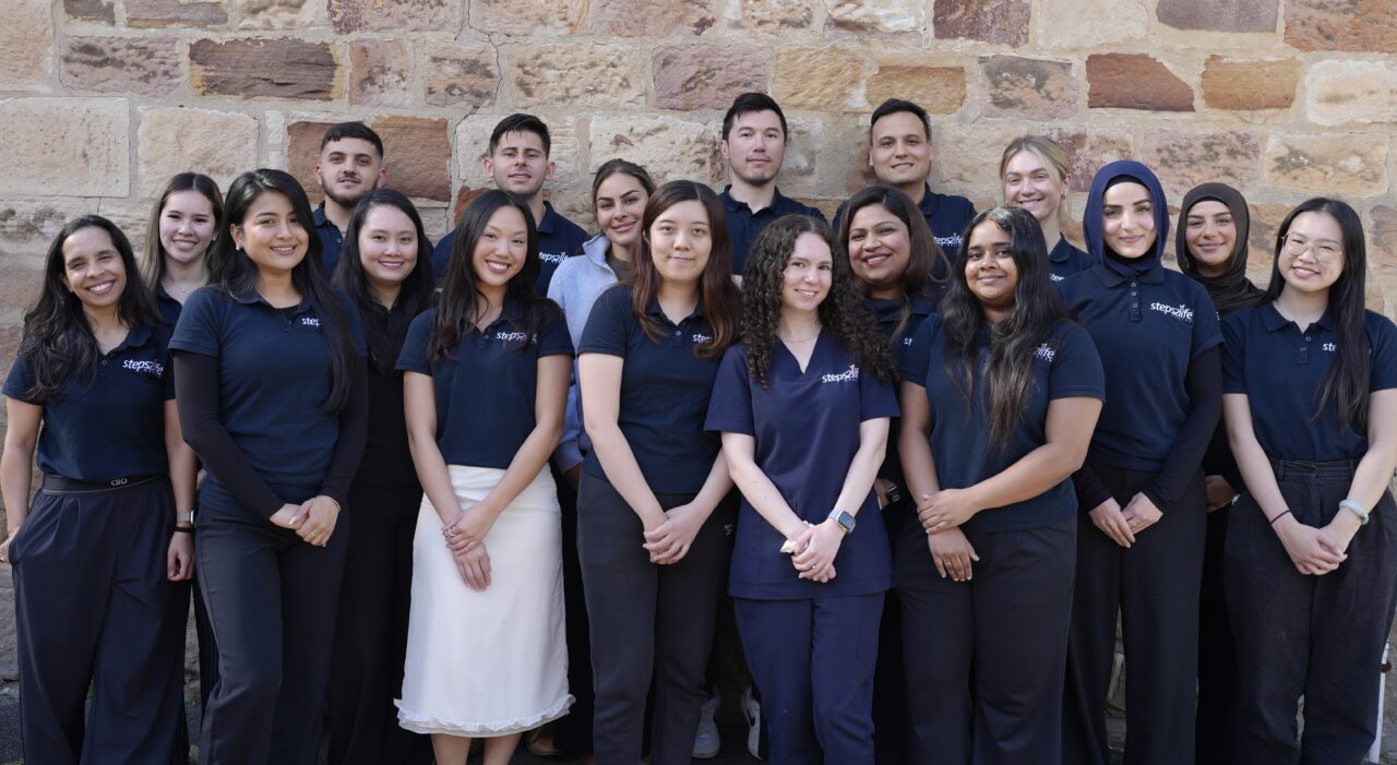 Steps2Life team standing together in front of a stone wall