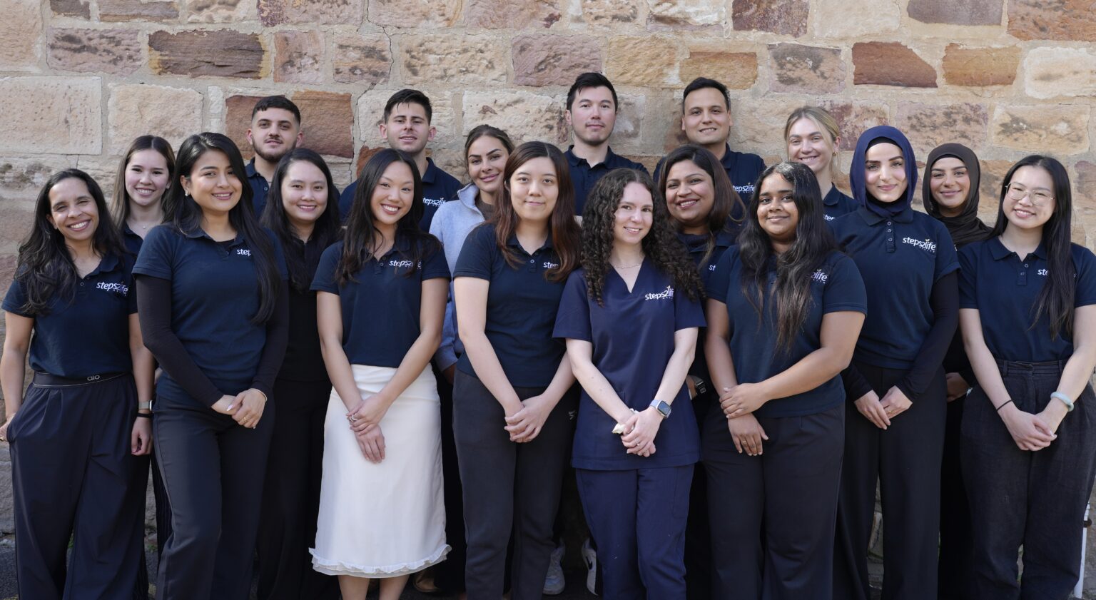 Steps2Life team standing together in front of a stone wall